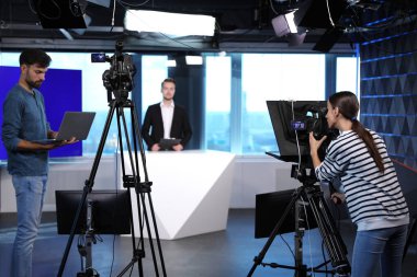 Sunucu, yönetmen ve video kamera operatörü stüdyoda çalışıyor. Haber yayını