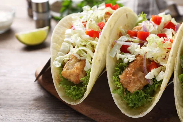 Yummy fish tacos served on wooden table, closeup