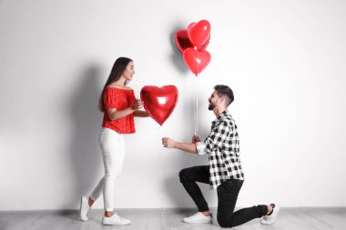 Işık duvarının yanında kalp şeklinde balonları olan mutlu genç bir çift. Sevgililer Günü kutlaması