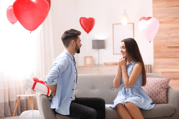 Genç Adam Oturma Odasında Kalp Şeklinde Balonlarla Süslenmiş Kız Arkadaşına — Stok fotoğraf
