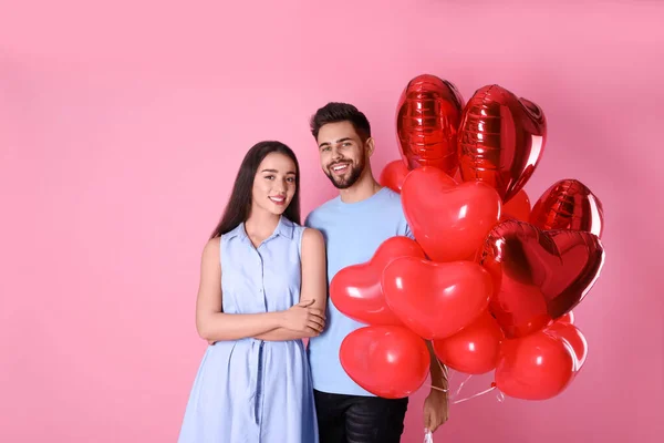 Lovely couple with heart shaped balloons on pink background. Valentine\'s day celebration