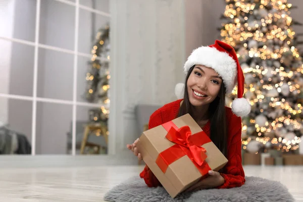 快乐的年轻女人戴着圣诞礼帽在家里 — 图库照片