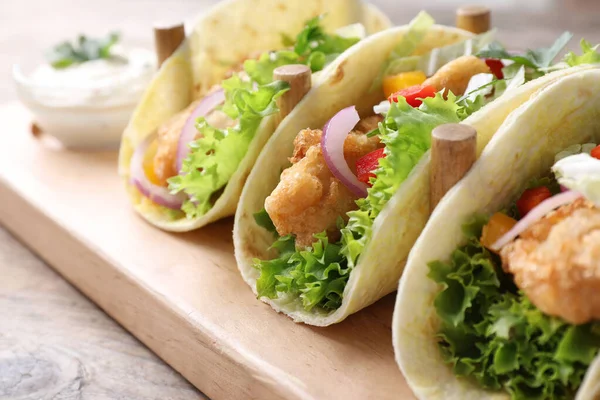Yummy fish tacos on wooden table, closeup