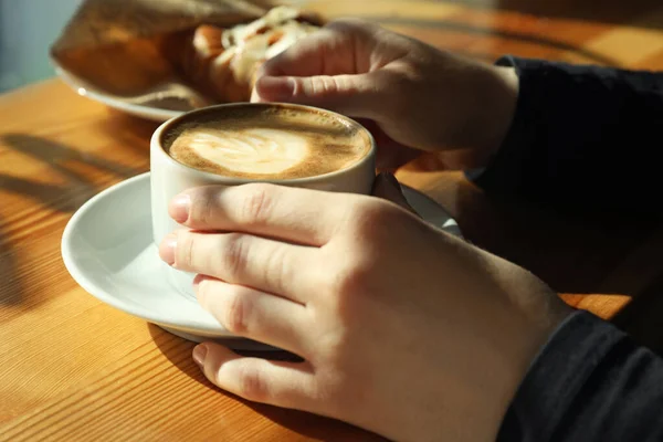 カフェのテーブル席で新鮮な香りのコーヒーを飲む女性 — ストック写真