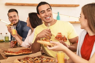 Bir grup arkadaş kafede lezzetli pizzalarla eğleniyorlar.