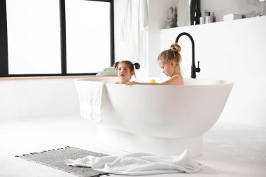Şirin küçük kız kardeşler evde birlikte banyo yapıyorlar.