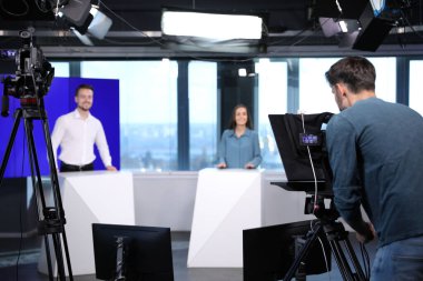 Sunucular ve kamera operatörü stüdyoda çalışıyor. Haber yayını