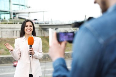 Şehir caddesinde çalışan genç gazeteci ve video operatörü