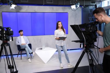 Sunucular ve kamera operatörü stüdyoda çalışıyor. Haber yayını