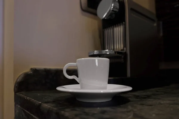 Copa blanca cerca de la máquina de café en la mesa — Foto de Stock