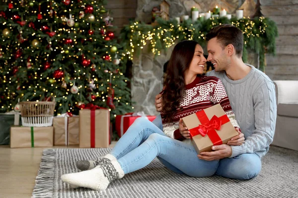 クリスマスのために飾られたリビングルームのギフトボックス付きの幸せなカップル — ストック写真