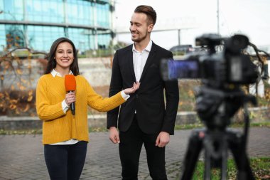 Genç gazeteci şehir sokaklarında iş adamıyla röportaj yapıyor.