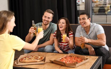 Bir grup arkadaş kafede lezzetli pizzalarla eğleniyorlar.