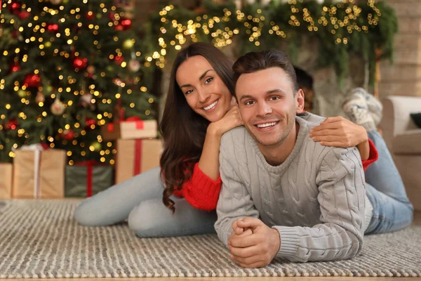 幸せな若いカップルはクリスマスのために飾られたリビングルームに床に横たわっています — ストック写真