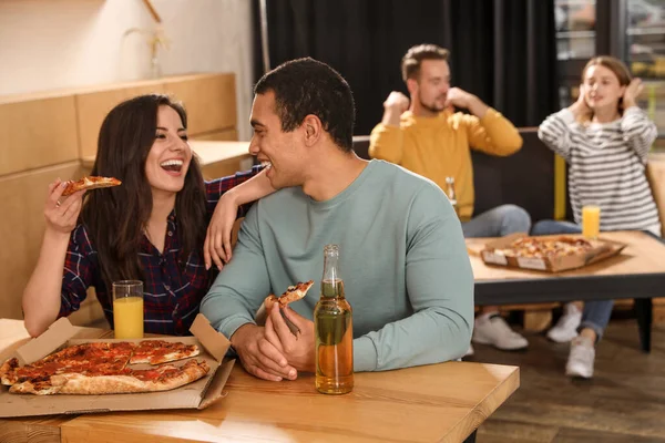 一对年轻夫妇在咖啡馆里吃着美味的披萨 — 图库照片
