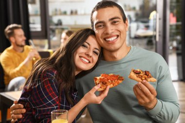 Kafede lezzetli pizzalar yiyen genç çift.