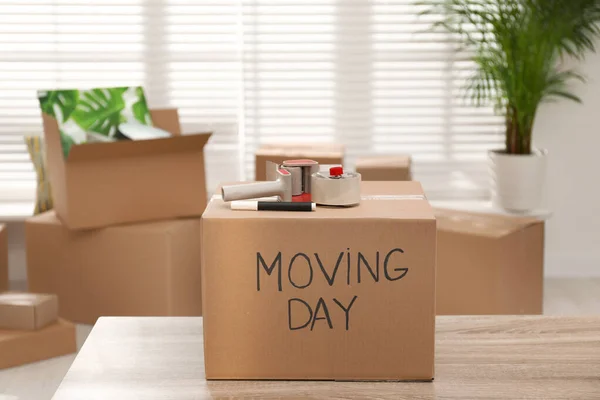 Cardboard box with words MOVING DAY and packaging items on woode — Stock Photo, Image