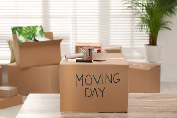 Scatola di cartone con parole MOVING DAY e articoli da imballaggio su legno — Foto Stock