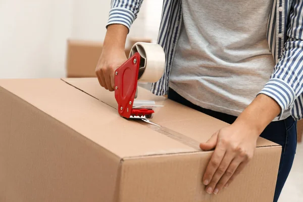Woman packing cardboard box indoors, closeup. Moving day — Stock Photo, Image