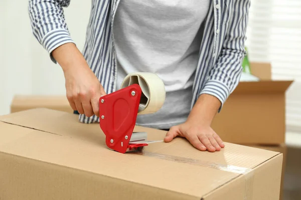 Mujer embalaje caja de cartón en el interior, primer plano. Día en movimiento — Foto de Stock