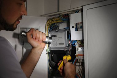 Fenerli elektrikçi içeride elektrik panelini tamir ediyor, yakın plan.