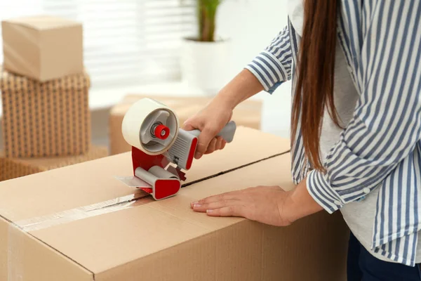 Woman packing cardboard box indoors, closeup. Moving day — Stock Photo, Image