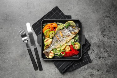 Lezzetli kızarmış balık ve sebzeler gri masada, düz yerde.