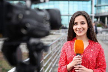 Mikrofonlu genç bayan gazeteci şehir sokaklarında çalışıyor.