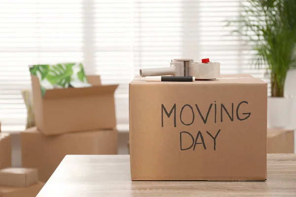 Caja de cartón con palabras MOVING DAY y artículos de embalaje en madera —  Fotos de Stock