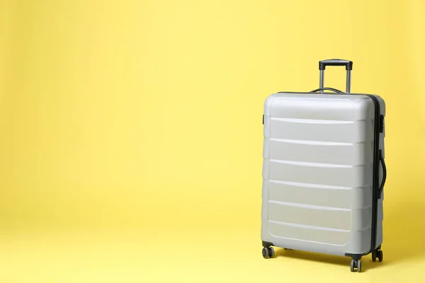 Stylish grey suitcase on yellow background. Space for text — Stock Photo, Image