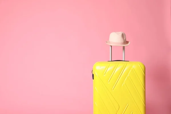Gelber Koffer mit Hut auf rosa Hintergrund. Raum für Text — Stockfoto