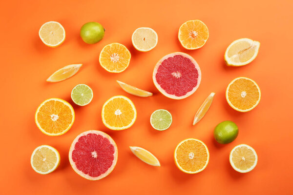 Flat lay composition with tangerines and different citrus fruits on orange background