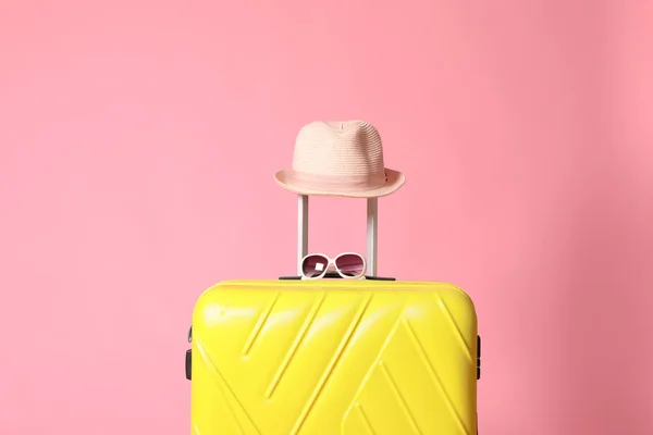 Gelber Koffer mit Sonnenbrille und Hut auf rosa Hintergrund — Stockfoto