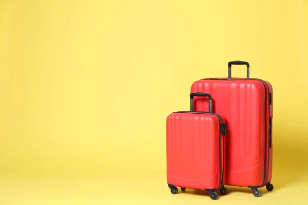 Stylish red suitcases on yellow background. Space for text — Stock Photo, Image