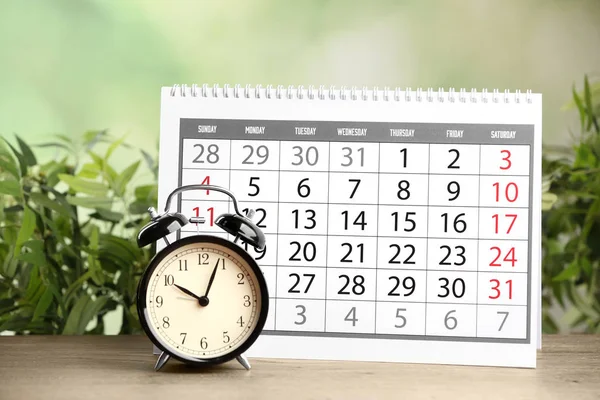 Kalender Und Wecker Auf Holztisch Vor Verschwommenem Grünem Hintergrund — Stockfoto