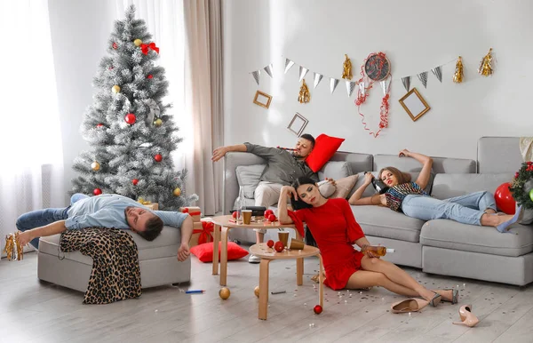 Friends suffering from hangover in messy room after New Year party