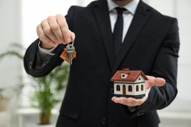 Emlakçı evin modelini ve anahtarını içeride tutuyor, yakın plan.