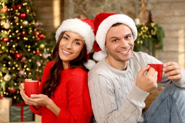 Oturma odasında Noel için süslenmiş bardakları olan mutlu çift.