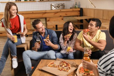 Bir grup arkadaş kafede lezzetli pizzalarla eğleniyorlar.