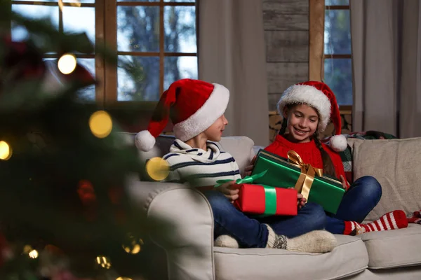 Glückliche Kinder Mit Weihnachtsmützen Und Weihnachtsgeschenken Auf Dem Heimischen Sofa — Stockfoto