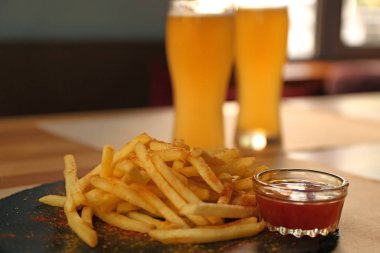Masada servis edilen kırmızı soslu leziz patates kızartması.