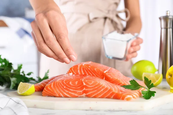 Femme salant du saumon cru frais à table, gros plan. Délicatesse de poisson — Photo