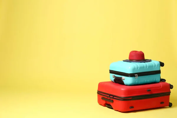 Stylish suitcases with hat on yellow background. Space for text — Stock Photo, Image