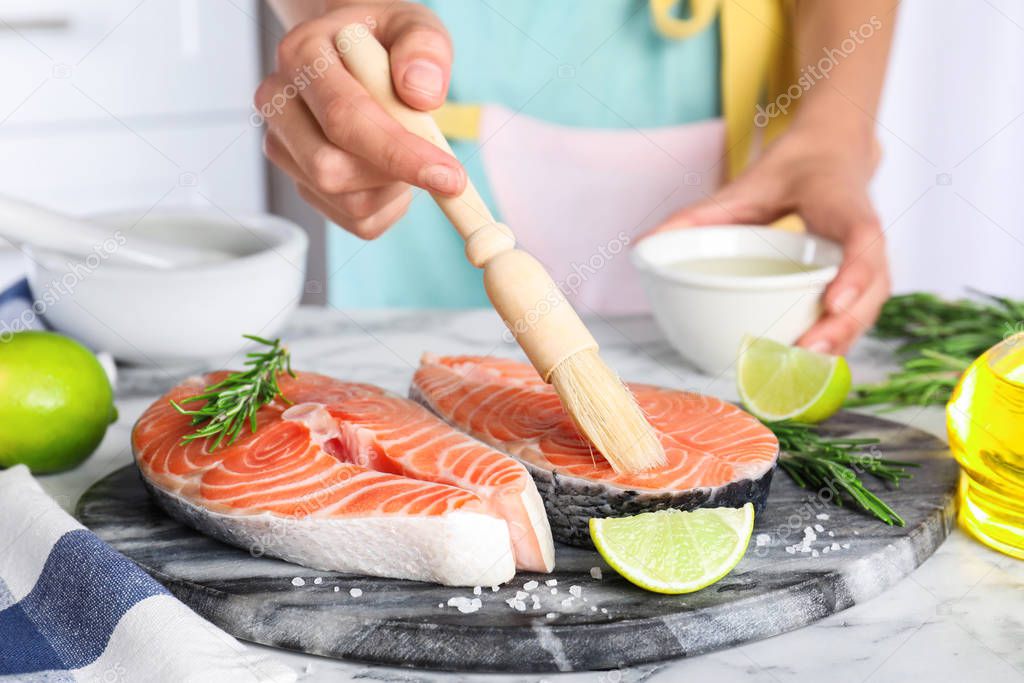 Woman marinating fresh raw salmon at table, closeup. Fish delica