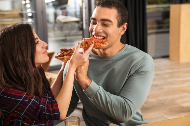 Kafede lezzetli pizzalar yiyen genç çift.