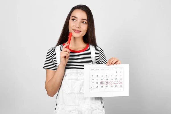 Молодая Женщина Проводит Календарь Отмеченными Днями Менструального Цикла Светлом Фоне — стоковое фото