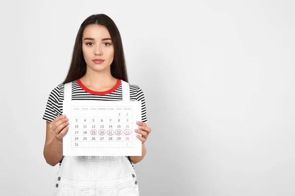 Ung Kvinna Som Håller Kalender Med Markerade Menstruationscykel Dagar Ljus — Stockfoto