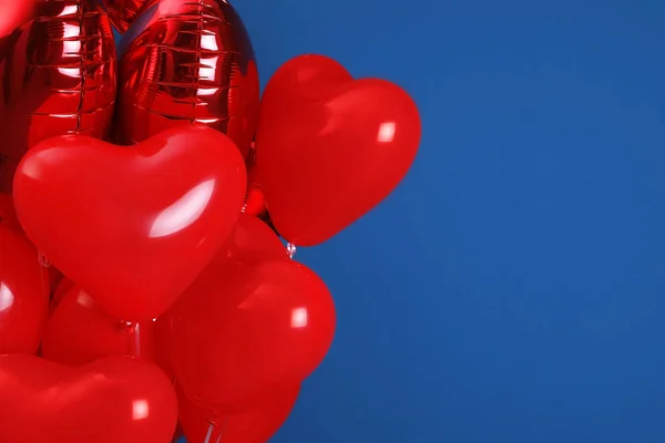Bunch of heart shaped balloons for Valentine\'s day celebration on blue background, closeup. Space for text