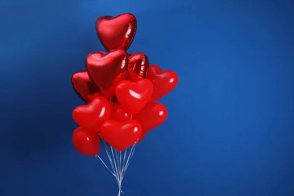 Bunch of heart shaped balloons on blue background, space for text. Valentine\'s day celebration