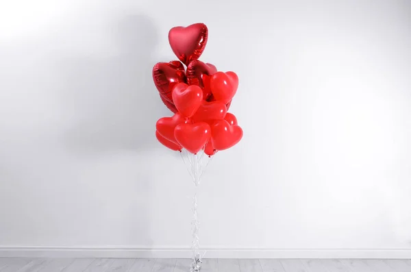 Bunch of heart shaped balloons near white wall. Valentine\'s day celebration